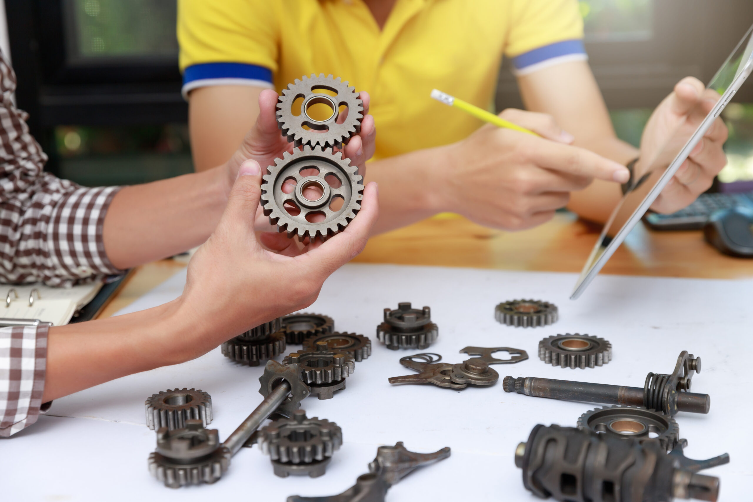 Engineer discussing and designing about mechanical gear parts in office.